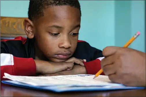  ?? (AP/Mark Humphrey) ?? Christian Ensrud, 7, watches Nov. 21 as his mother, Tamela Ensrud, help him with his homework at their home in Nashville, Tenn.