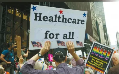  ??  ?? 支持全民健保的民眾2­9日在紐約川普大廈外­面舉牌示威。(Getty Images)