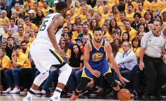  ?? REUTERS PIC ?? Warrior Stephen Curry (right) tries to go past Jazz’ s Derrick Favors during their game in Los Angeles on Monday.