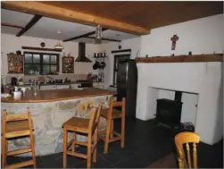  ??  ?? Open plan kitchen with old- style fireplace and stove and whitewash design