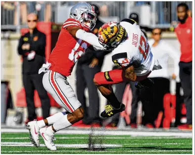  ?? GETTY IMAGES ?? Cornerback Denzel Ward rocks Maryland receiver Taivon Jacobs after a first-quarter reception Saturday at Ohio Stadium. Ward forced a fumble and returned it for a touchdown, only to be erroneousl­y penalized for targeting.