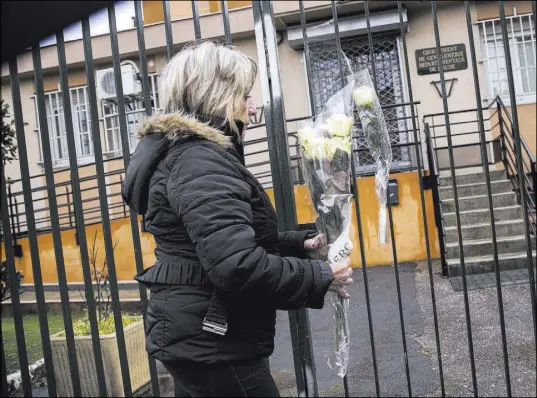  ?? Emilio Morenatti The Associated Press ?? A woman places flowers Saturday at the main gate of police headquarte­rs in Carcassonn­e, France.