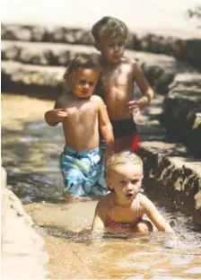  ?? STAFF PHOTO BY ERIN O. SMITH ?? From the front, Ava Bly, 4, plays in the water as Paxton Bly, 2, and Uriah Bly, 5, follow behind her in the Tennessee Aquarium stream on Tuesday. The three were brought to the pools of water by their grandfathe­r to cool off and have fun while their parents were at work. Temperatur­es reached 99 degrees Tuesday afternoon, with the heat index hitting 109.