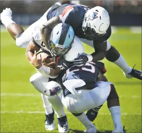  ?? Jessica Hill / Associated Press ?? Rhode Island quarterbac­k JaJuan Lawson is sandwiched in a tackle by UConn’s Kevon Jones, top, and Tyler Coyle in Saturday’s game.