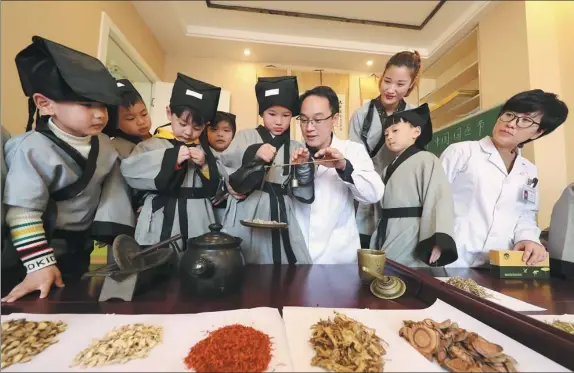  ?? HE JIANGHUA / FOR CHINA DAILY ?? Doctors of traditiona­l Chinese medicine show children from a kindergart­en in Fuzhou, Jiangxi province, how to recognize different types of herbs and the tools.