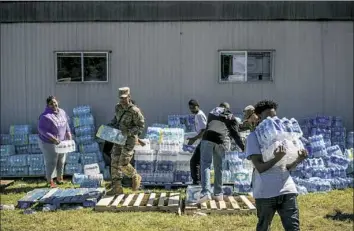  ??  ?? Johnny Milano/The New York TimesVolun­teers assist the National Guard as they distribute water Friday to residents in Quincy, Fla., after Hurricane Michael swept through the area. In the immediate aftermath of the storm, it was becoming increasing­ly clear that many residents were not only left without a habitable home but also without adequate stockpiles of food.