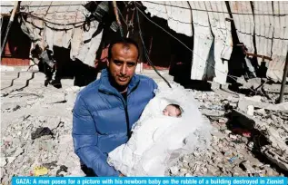  ?? — AFP ?? GAZA: A man poses for a picture with his newborn baby on the rubble of a building destroyed in Zionist bombing in Rafah in the southern Gaza Strip on Feb 11, 2024.