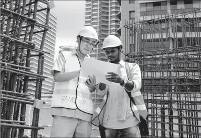  ?? PROVIDED TO CHINA DAILY ?? A CRCG engineer instructs a foreign apprentice on constructi­on technology essentials at Four Seasons Hotel constructi­on site in Malaysia in 2015. The building is the tallest overseas structure built by CRCG.