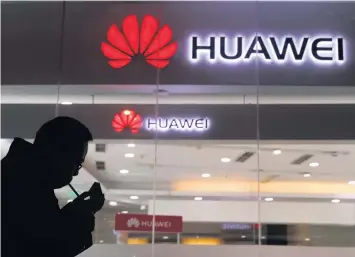  ?? AP ?? Un hombre enciende un cigarrillo afuera de una tienda Huawei en Pekín.