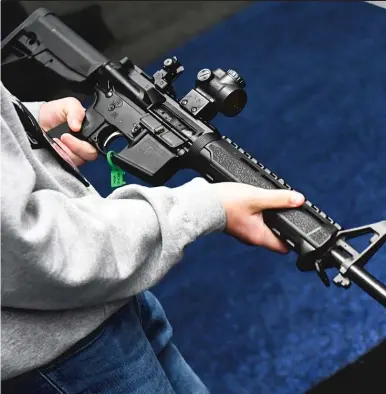  ?? PATRICK T. FALLON/AFP VIA GETTY IMAGES ?? An attendee holds a Springfiel­d Armory SAINT AR-15-style rifle displayed during the National Rifle Associatio­n Annual Meeting in Houston on May 28.