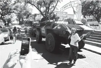  ?? (Mark Balmores) ?? DESPITE the tension that has gripped the region, a lady is still able to find time to take a selfie in front of an Armored Personnel Carrier (APC) that is positioned within the Davao City Hall area.