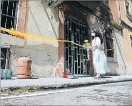  ?? XAVIER CERVERA ?? Dol al barri. Una veïna s’acosta al ja maleït número 16 de Grau i Torras a deixar unes flors en homenatge a les víctimes