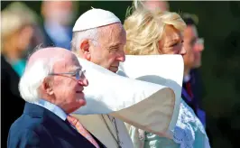  ??  ?? Pope Francis is flanked Saturday by Irish President Michael D. Higgins, left, and the president’s wife, Sabina, upon his arrival at the presidenti­al residence in Dublin. Francis is on a two-day visit to Ireland.