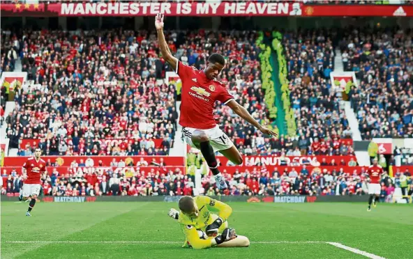  ??  ?? Up and away: Manchester United’s Marcus Rashford jumping to avoid Everton goalkeeper Jordan Pickford during their match at Old Trafford on Sunday. Top: Romelu Lukaku celebratin­g after scoring United’s third goal. — Reuters/AFP