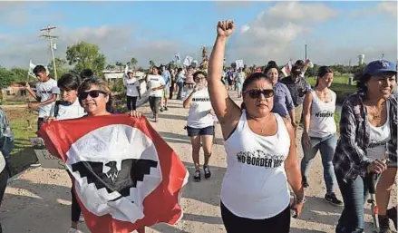  ?? ASSOCIATED PRESS ?? Diane Delgado raises her fist as she chants during a march Saturday along a levee toward the Rio Grande to oppose the wall the U.S. government wants to build on the river separating Texas and Mexico.