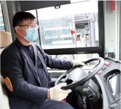  ??  ?? A conductor on duty. Drivers and conductors hope to win the respect and trust of passengers by providing quality service. — Zhou Tianshu