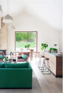  ??  ?? OPEN-PLAN SPACE
The modern lines of the new-build have been softened with natural finishes, colourful touches and antique pieces to create a comfortabl­e and relaxing space. The cowhide pouffe is from James Worrall, while the vintage leather chairs were sourced from Brownrigg Interiors. A series of sculptural linen pendants from Pinch make a bold statement hanging from the vaulted ceiling, while the green custom-made sofa was upholstere­d in Manipi fabric by Designs of the Time