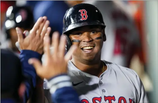  ?? LINDSEY WASSON — THE ASSOCIATED PRESS ?? Boston Red Sox’s Rafael Devers is greeted in the dugout after his two-run home run against the Seattle Mariners during the third inning of the season-opening game March 28in Seattle.