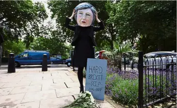  ??  ?? Big headache: A demonstrat­or wearing a mask depicting May, posing with a mock gravestone during a protest near the Houses of Parliament in central London. — AFP