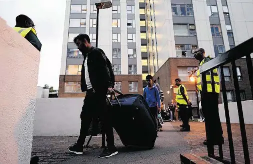  ??  ?? CHAOTIC: Residents leave Taplow tower block on the Chalcots Estate in Camden as the building is evacuated for urgent fire safety works