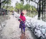  ?? MAHMUD HOSSAIN OPU AP ?? A young girl must wait for low tide and for the roads to become visible before she can walk safely home from school in Pratap Nagar in the Shyamnagar region of Bangladesh.