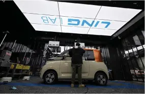  ?? ?? A worker applying a wrapping to a mini electric vehicle at a car modificati­on centre in Liuzhou, in southern China’s Guangxi province.