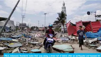  ?? — AFP ?? PALU, Indonesia: Residents make their way along a street full of debris after an earthquake and tsunami hit Sulawesi island yesterday.