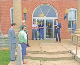  ?? STAFF PHOTO BY DAVE FLESSNER ?? Dunlap, Tenn., attorney Thomas Austin leads the foreclosur­e sale of the shuttered Textile Corp. of America plant in Pikeville at the entrance of the Bledsoe County Courthouse in July 2019. Standing in the foreground on the left are attorney Lance Pope and his client, Karim Sadruddin, the CEO of Textile Corp. of America.