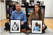  ?? AP PHOTO/CLIFF OWEN ?? Bryan and Julie Hanlon hold photos of their adopted Haitian children, Gina, left, and Peterson, on Tuesday in a play area of their home in Washington.