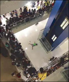  ??  ?? Mallgoers look at the body of Madonna Guanzon at a mall in Mandaluyon­g City Sunday, in this photo taken by a netizen. Photos and videos of Guanzon’s suicide on Valentine’s Day have gone viral on the Internet.