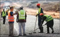  ?? ZHOU XIAOXIONG / XINHUA ?? A Chinese engineer consults with local workers at a road constructi­on site in