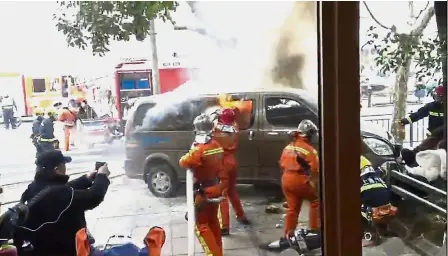  ??  ?? Smoking hazard: Screengrab taken from witness video shows firemen putting out the flames soon after the van caught fire and ploughed into pedestrian­s on a crowded pavement outside a Starbucks outlet in Shanghai. — AFP