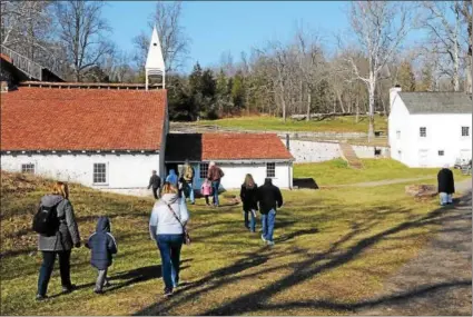  ?? JOHN STRICKLER – DIGITAL FIRST MEDIA ?? Families walk through the Hopewell Furnace National Historic Sites during the ‘Iron Plantation Christmas’ event Saturday. It gave the public a chance to see the simple elegance of Christmas through the years from 1795to 1880.