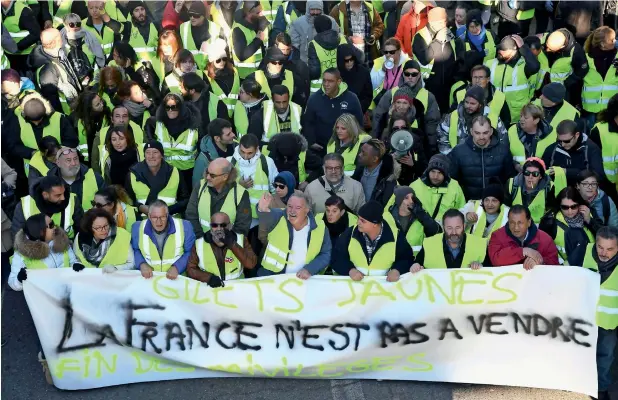  ?? AFP ?? Protesters wearing yellow vests hold a sign reading ‘France is not for sale’ during a demonstrat­ion in Marseille, southern France, on Saturday. —