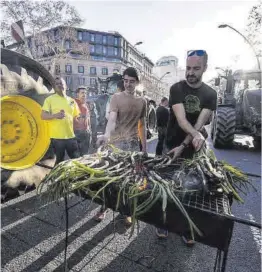  ?? Zowy Voeten ?? Un grupo de agricultor­es cocinan ‘calçots’, ayer en Barcelona.