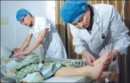  ?? GAO BO / FOR CHINA DAILY ?? Yang Bin (right) and another male nurse tend to a patient at the Hefei Binhu Hospital.