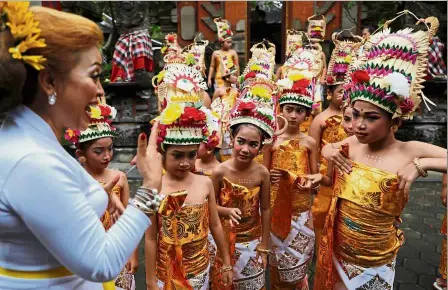  ?? — Reuters ?? Getting ready: Balinese girls being briefed before they perform the Rejang Dewa dance during a ritual before the holy day of Nyepi in Jakarta, Indonesia.