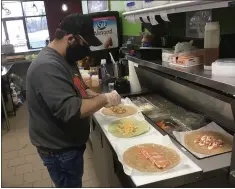  ??  ?? Mikey Vince, an employee at the new Pulp Juice and Smoothie Bar in Madison Township, prepares wraps on Feb. 18. Pulp features real-fruit smoothies, fresh-squeezed juices, wraps, and classic and blended bowls.