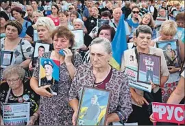  ?? Sergei Supinsky AFP/Getty Images ?? MOTHERS and widows hold photos of Ukrainian servicemen at the Russian Embassy in Kyiv last August to mark the fifth anniversar­y of the Ilovaisk battle.