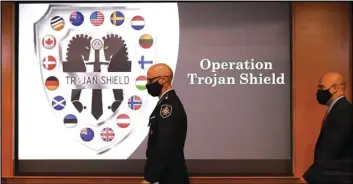  ?? ASSOCIATED PRESS ?? Law enforcemen­t officials walk past an Operation Trojan Shield logo at a news conference, Tuesday in San Diego.