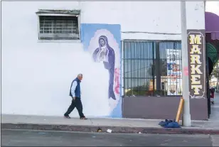  ?? OSCAR RODRIGUEZ ZAPATA VIA AP ?? A man walks next to a partially-covered Virgin of Guadalupe mural in Los Angeles in 2018. January marked 10years since Oscar Zapata began documentin­g images of Guadalupe like this one.