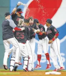 ?? Ron Schwane, Getty Images ?? Jay Bruce, who doubled in the winning run in the 10th inning, is mobbed by his Indians teammates.
