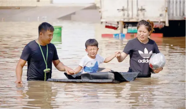  ?? Reuters ?? A child sits on a makeshift raft on a flooded road following heavy rainfall in Zhengzhou on Thursday.