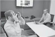  ?? P. SOLOMON BANDA, THE ASSOCIATED PRESS ?? Nick Harrell holds up a pair of virtual reality goggles to treat his fear of flying at the National Mental Health Innovation Center in Aurora, Colorado. Behavioral health scientist Sam Hubley is at right.