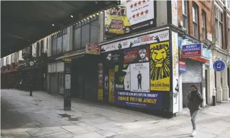  ??  ?? A pedestrian walks through the near-empty West End district in London. With continuing restrictio­ns on social gatherings due to the COVID-19 pandemic, there’s no prospect of live theatre opening again soon.