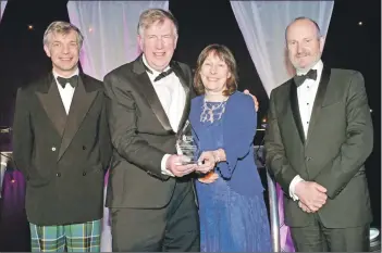  ??  ?? Stuart and Liz Blake of the Lochranza Centre CIC receive their award from Robert Scott-Dempster, category sponsor, and host Fred MacAulay, right.