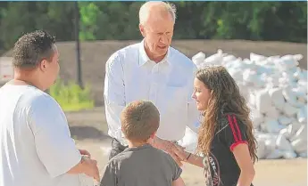  ?? | PAUL VALADE/ DAILY HERALD ?? South Elgin resident Manuel Ramirez ( left) brought his children Caleb, 11, and Cadence, 12 ( right), to volunteer filling sandbags Sunday at the Algonquin public works facility. While working, theywere thanked by Gov. Bruce Rauner.