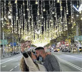  ?? Manu Mitru ?? Una pareja se besa bajo la iluminació­n navideña del paseo de Gràcia.