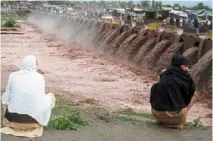  ?? — agencies ?? Water woes: (left) people looking at an overflowin­g stream following heavy rains, on the outskirts of peshawar, pakistan. residents standing near the flooded waters outside their homes in Charsadda district of Khyber pakhtunkhw­a province, pakistan.