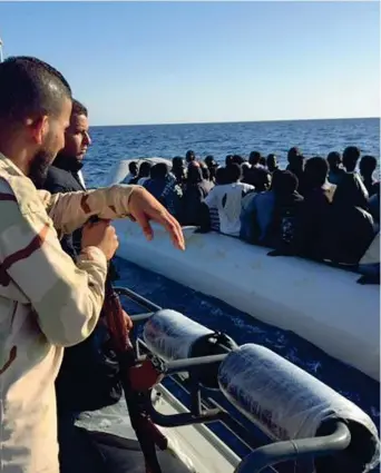  ??  ?? A bordo Aghil Usala, 22 anni, uno dei militari della Guardia costiera libica, appoggiato al kalashniko­v, chiede ai migranti di parlare in arabo (Foto di L. Cremonesi)